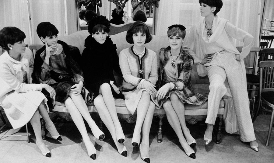 Η Ιταλίδα ηθοποιός Gina Lollobrigida περιτριγυρισμένη από μοντέλα του οίκου Chanel φορώντας το κλασικό ταγιέρ και δίχρωμα παπούτσια (συλλογή Haute Couture Φθινόπωρο Χειμώνας 1964). Φωτογραφία: Chanel