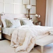 Μία κρεβατοκάμαρα με λευκό και στοιχεία γήινα και χρυσαφί δίνει τόνο πολυτέλειας που ενισχύεται με μία λευκή γούνα ριγμένη στο κρεβάτι που είναι και πολύ της μόδας